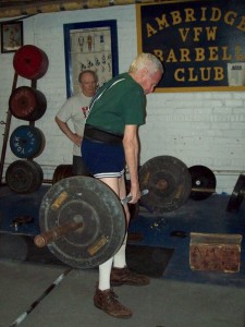 Dennis Mitchell performing a One Arm Deadlift at the Ambridge Barbell Club, under the watchful eye of John McKean.